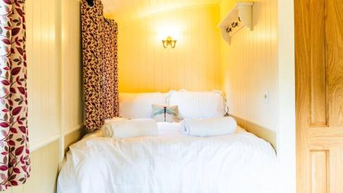 a bedroom with a bed with white sheets and pillows at La Rouge Roulotte in Hassocks