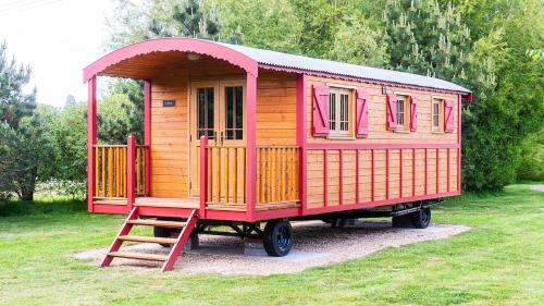 a red and wooden train car sitting in the grass at La Rouge Roulotte in Hassocks
