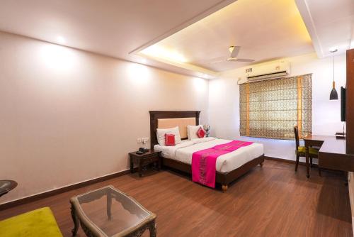 a bedroom with a bed and a desk and a table at HotelMaple Ridge in Tājganj