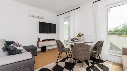 a living room with a table and chairs and a tv at Perła Mierzei, Sun & Snow in Sztutowo