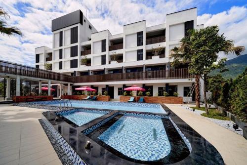 a hotel with two pools in front of a building at Yen Hotspring in Ruisui