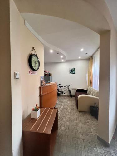 a living room with a couch and a clock on the wall at Family Hotel Square in Ruse
