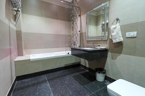 a bathroom with a sink and a tub and a toilet at HotelMaple Ridge in Tājganj