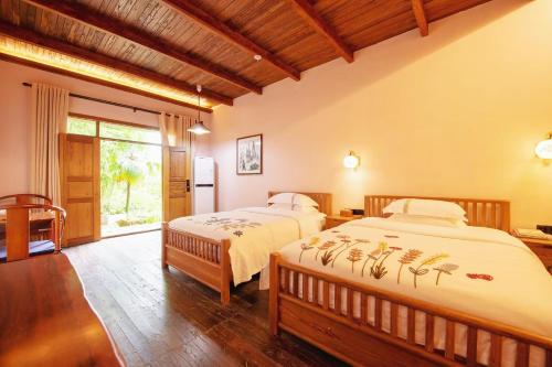 a bedroom with two beds and a window at Dayong Antique Feature Resort in Zhangjiajie
