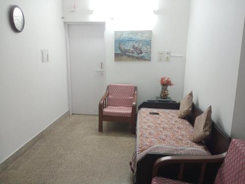 a room with a couch and a chair and a clock at Alice's Cozy Abode in Udupi