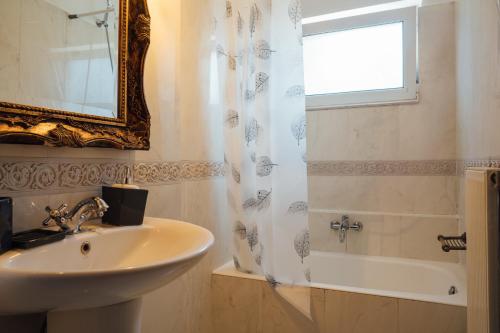 a bathroom with a sink and a mirror and a shower at Elegant 3BR Seaside Home with Great View in Mytilini
