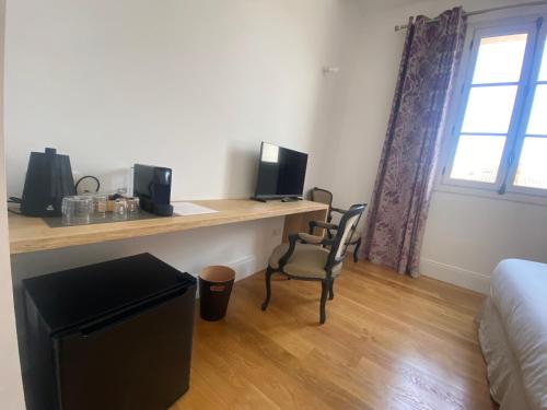 a room with a desk with a bed and a window at La Hugotine in Marseillan