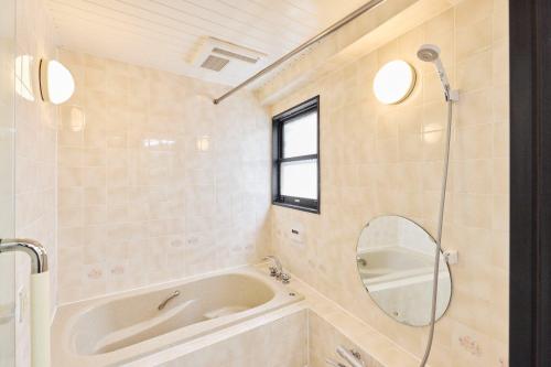 a bathroom with a tub and a sink and a mirror at Fujimigaoka Detached House A in Kugayama