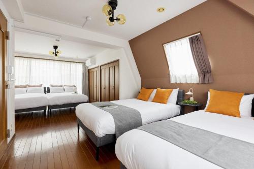 a hotel room with three beds and windows at Fujimigaoka Detached House A in Kugayama