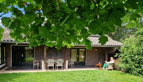 a woman sitting on the porch of a house at Rozenhofje Asselt - Roermond in Swalmen