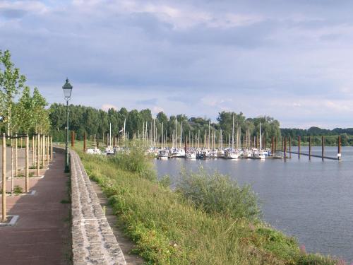 a row of boats on a river with a dock at Rozenhofje Asselt - Roermond in Swalmen