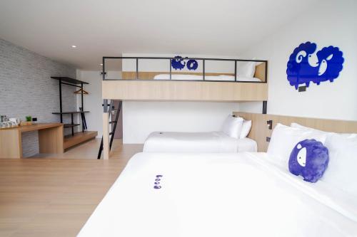 a bedroom with two bunk beds and a desk at Kokotel Rayong Beachfront in Ban Pak Khlong Phe