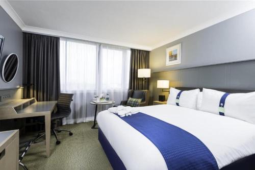 a hotel room with a large bed and a desk at Holiday Inn - Glasgow Airport by IHG in Paisley