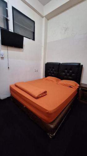a bedroom with a bed with an orange blanket at Viola in Bukittinggi