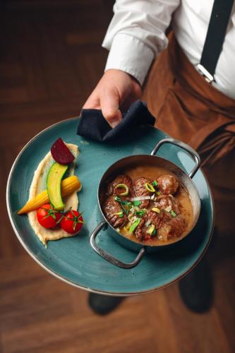 a person holding a plate with a bowl of food at Van der Valk Hotel Groningen-Westerbroek in Westerbroek