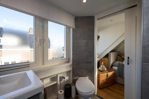 a bathroom with a sink and a toilet and a window at Large vacation home with garden near the sea and Haarlem in Overveen