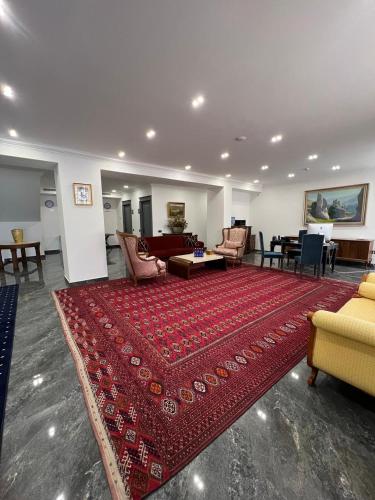 a living room with a large red rug on the floor at Plaza Viktoria Hotel Yerevan in Yerevan