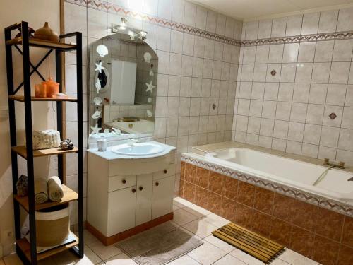 a bathroom with a tub and a sink and a mirror at Villa unique, 50 mètres du jardin au lac in Savines