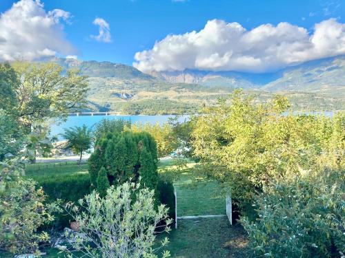 a garden with trees and a lake in the background at Villa unique, 50 mètres du jardin au lac in Savines