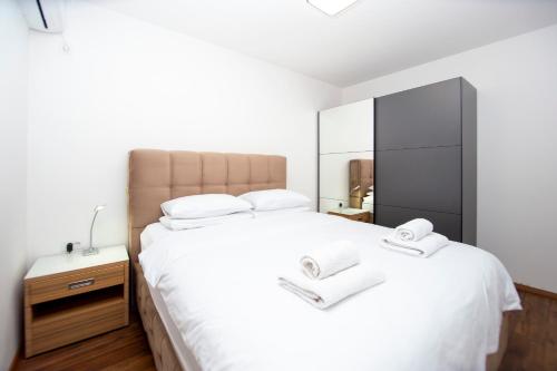 a bedroom with a large white bed and a mirror at Apartments Natasa in Sveti Stefan