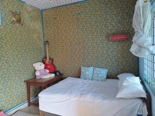 a bedroom with a bed and a teddy bear and a guitar at Anndam Yoga and Mediation House in Deorāli