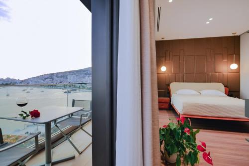 a room with a balcony with a bed and a table at Hotel Saranda Butrinti, Affiliated by Melia in Sarandë