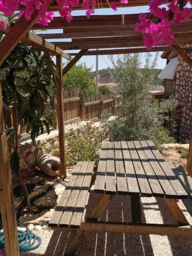 a wooden picnic table in a garden with pink flowers at Restored stone house with terrace and gardens in Demre