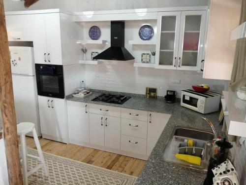 a kitchen with white cabinets and a stove top oven at Restored stone house with terrace and gardens in Demre