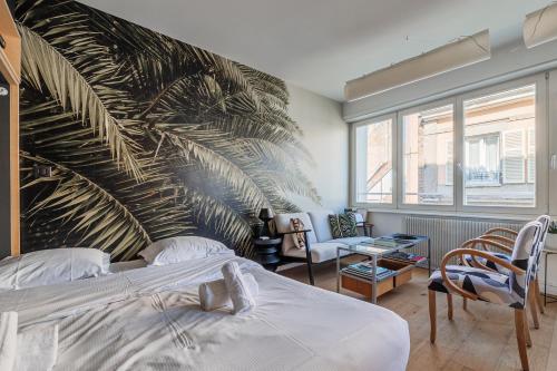 une chambre avec un grand mur avec une fresque de feuilles de palmier dans l'établissement L'Éclat Urbain - Studio dArchi Gare et Petite-France, à Strasbourg