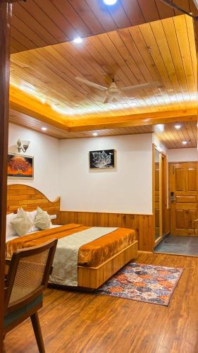 a bedroom with a large bed and a wooden ceiling at Hotel SNAS Retreat Manali in Manāli