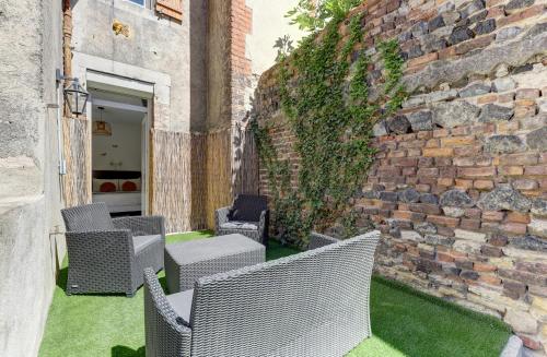patio z wiklinowymi krzesłami i ceglaną ścianą w obiekcie Forêt Urbaine - Jolie T3 avec terrasse w mieście Montluçon