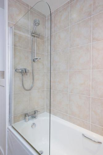 a bathroom with a shower with a glass door at Blaeberry Cottage in Aviemore