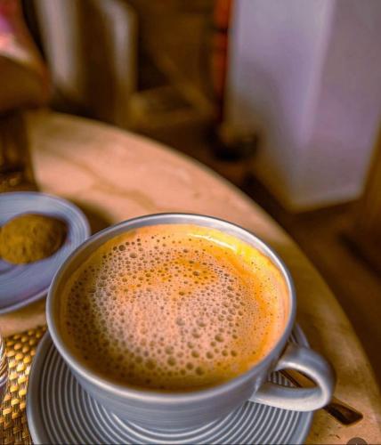 a cup of coffee sitting on a table at The Postcard Saligao in Calangute