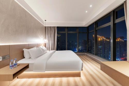 a bedroom with a large white bed and a large window at Xiyada Hotel（Chongqing Guanyinqiao） in Chongqing