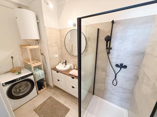 a bathroom with a shower and a sink and a washing machine at The North Apartment in Ljubljana