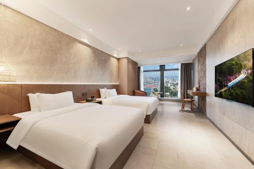 two beds in a hotel room with a large window at Xiyada Hotel（Chongqing Guanyinqiao） in Chongqing