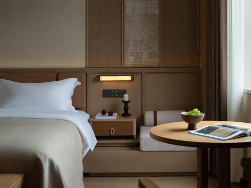 a hotel room with a bed and a table with a book at Yanyu Yunxi Resort Hotel 烟雨云兮酒店 in Fenghuang