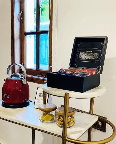 a tea kettle and a box on a shelf with cookies at The Postcard Saligao in Calangute