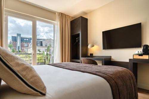 a hotel room with a bed and a large window at The Originals Boutique, Hôtel Les Coulisses du Théâtre, Saint-Quentin in Saint-Quentin