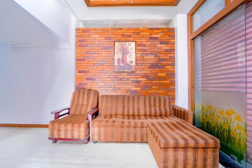 two chairs and a couch in front of a brick wall at Hotel O City Center Ernakulam in Cochin