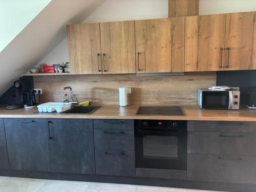 a kitchen with wooden cabinets and a sink and a microwave at Boardinghaus Koucha - Wohnen auf Zeit in Neuburg an der Donau