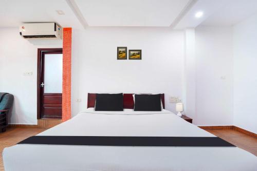 a bedroom with a white bed with black pillows at Hotel O City Center Ernakulam in Cochin