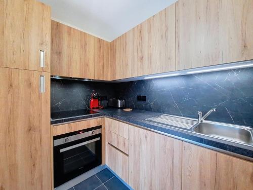 une cuisine avec des armoires en bois et un évier dans l'établissement Imperial IP402 COSY & VIEW 6 Pers, à Châtel