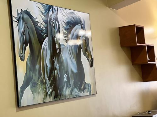 a painting of horses hanging on a wall at The Oasis in Buwate