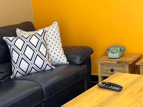 a black leather couch with pillows and a telephone on a table at The Oasis in Buwate