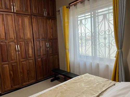 a bedroom with a bed and a window with wooden cabinets at The Oasis in Buwate