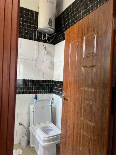 a bathroom with a toilet and a wooden door at The Oasis in Buwate