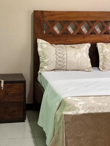 a bed with a wooden headboard and white pillows at The Oasis in Buwate