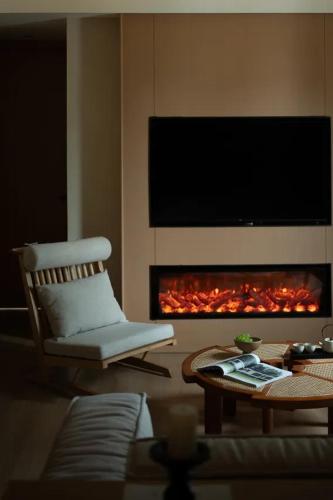 a living room with a chair and a fire place at Yanyu Yunxi Resort Hotel 烟雨云兮酒店 in Fenghuang