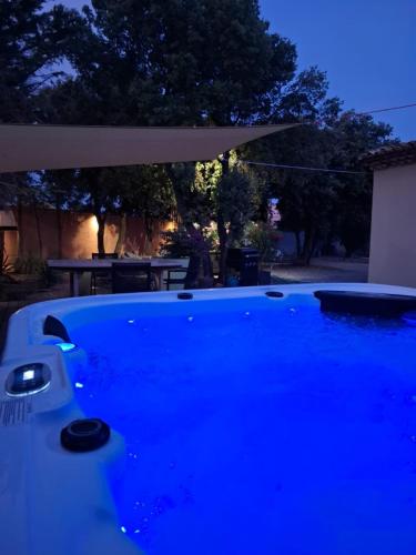 - une piscine bleue avec un parasol et une table dans l'établissement Location indépendante au cœur des Alpilles pour 2 personnes avec Jacuzzi, à Aureille